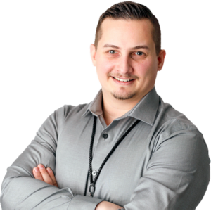 Portrait of Patrick Domingues, CEO of Zevonix, smiling with arms crossed while wearing a light gray button-down shirt.