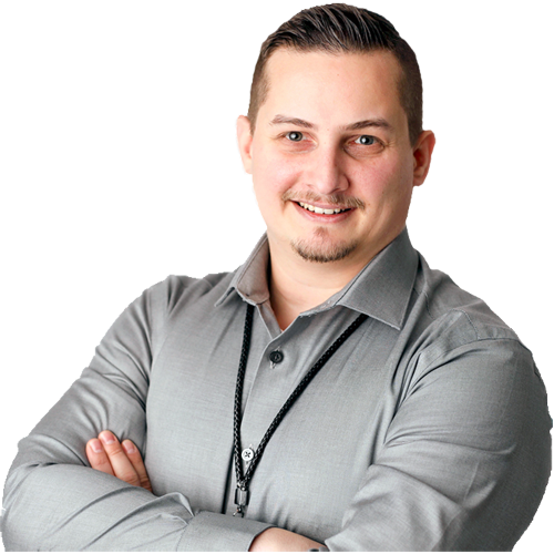 Portrait of Patrick Domingues, CEO of Zevonix, smiling with arms crossed while wearing a light gray button-down shirt.